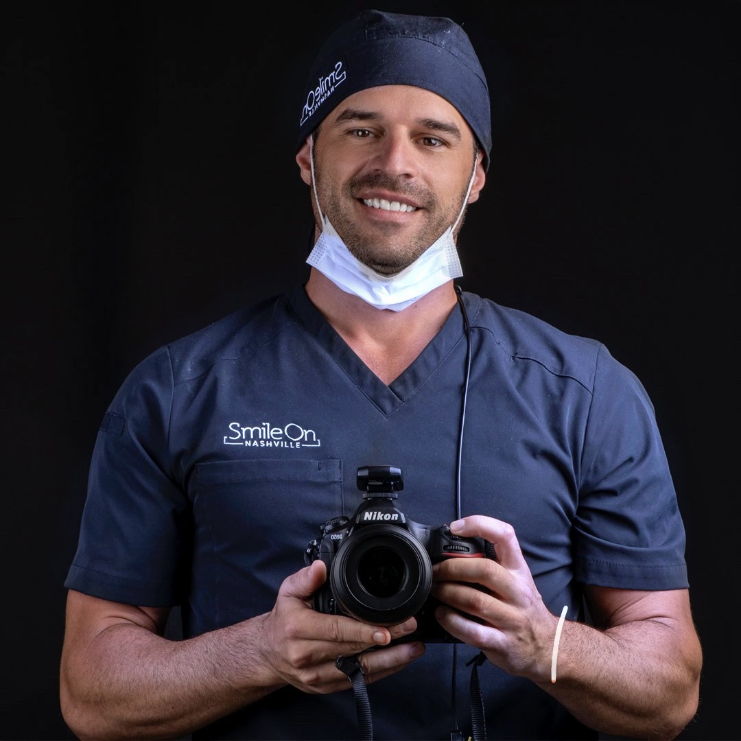 Dr. Jeff Trembley in surgical cap holding the camera he photographs every case with