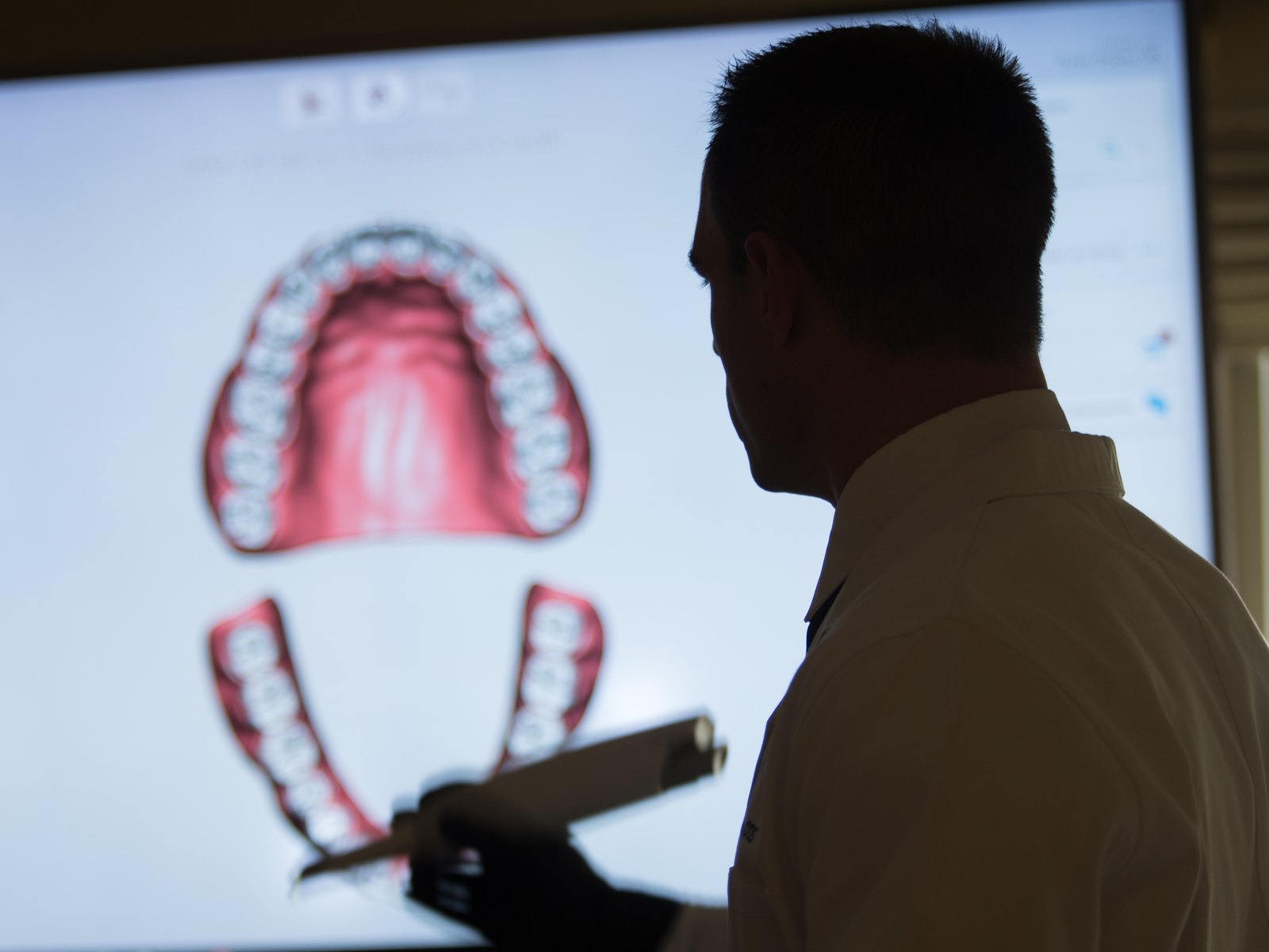 Dr. Jeff Trembley reviewing a digital smile design on a large screen in a darkened room